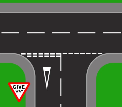 A give way junction from above. Two thick broken white lines run across the mouth of the minor road, a hollow white triangle is painted on the road behind them, and a red-bordered inverted triangle GIVE WAY sign stands on the corner. Broken hazard warning lines run along the centre of the major road.